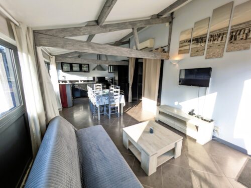Wohnzimmer der Cidrerie-Hütte, mit dem Sofa, dem Fernseher und der Küche.