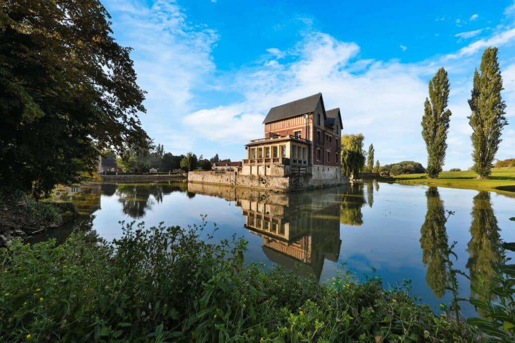 Vue du domaine avec les douves, le château et le parc boisé.