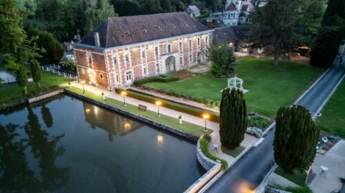 Luftaufnahme des Anwesens mit dem Wassergraben, dem Teichhaus, den Nebengebäuden und dem Park.